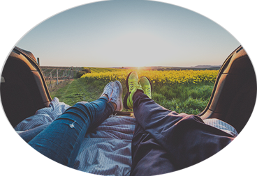 Oval photo of two pairs of feet stretched out watching the sunset